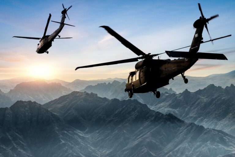 Two military helicopters flying over a mountain range, highlighting the need for DoD CMMC compliance.